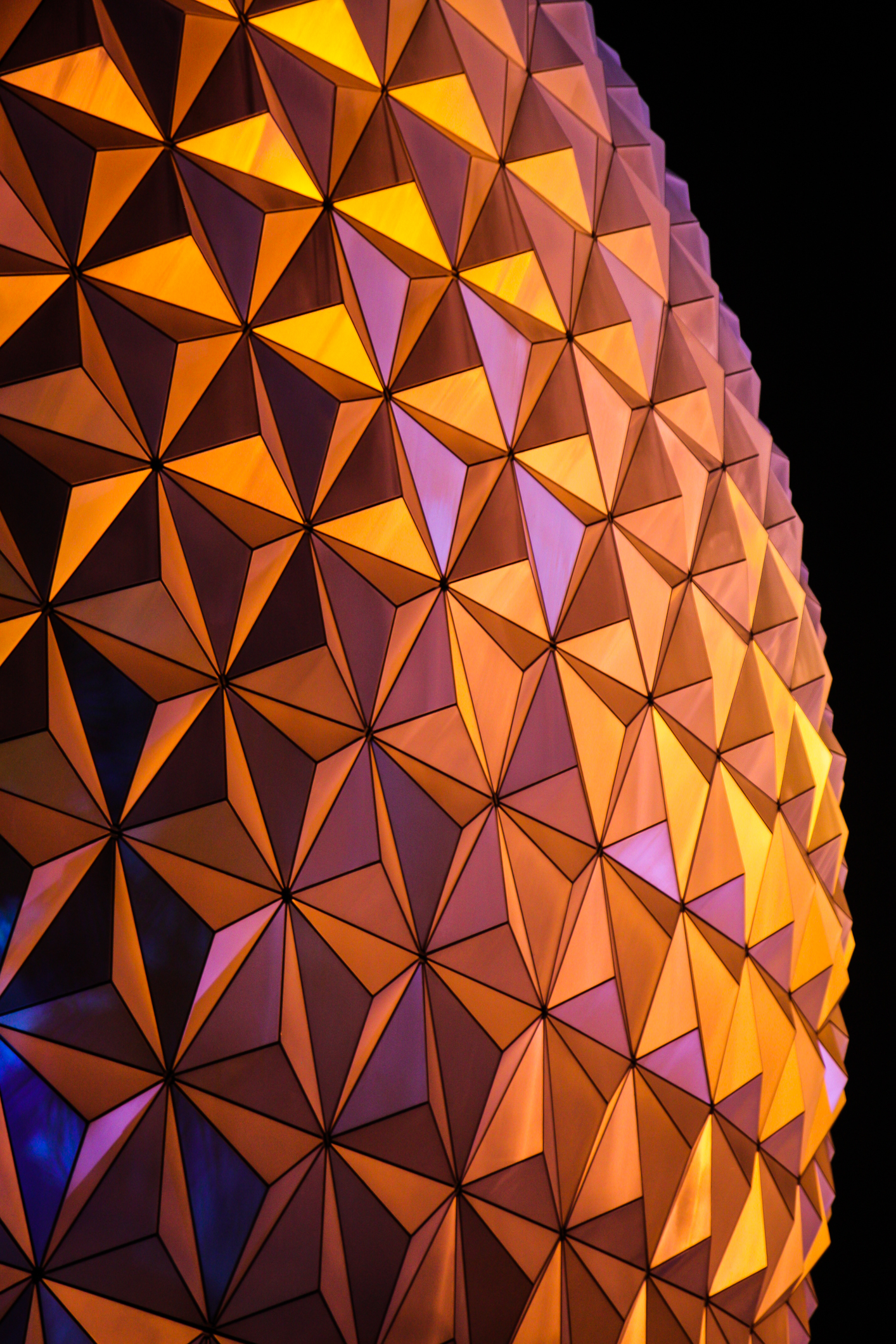 Disney World Epcot's Spaceship Earth glows with orange and yellow reflections at night NotSoSAHM