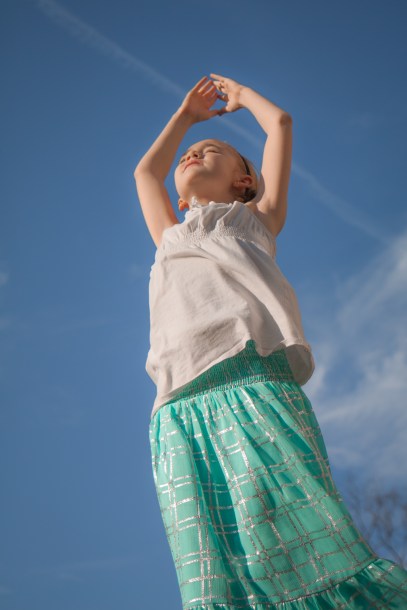 Girl soaks in the sun with hands raised above head NotSoSAHM