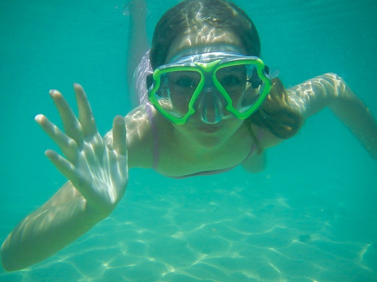 A girl waves to the camera underwater in Hawaii Not So SAHM