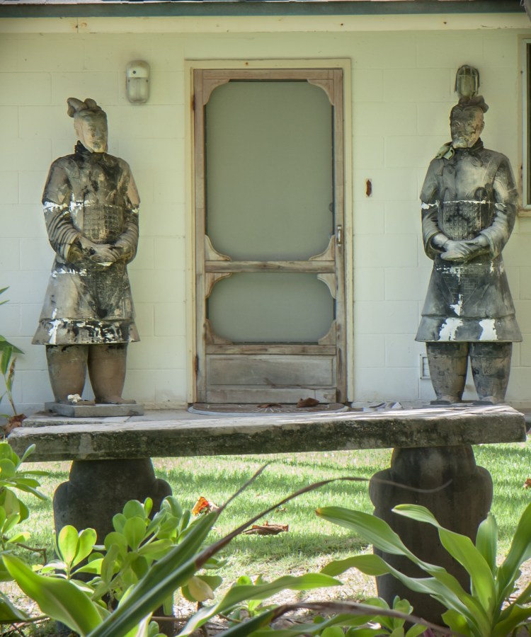 Two life-size asian statues stand on either side of a front door on a beach house on Oahu Not So SAHM