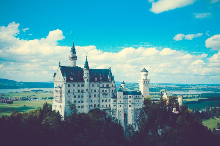 Schloss Neuschwanstein sits atop a hill with a bucolic backdrop. Not So SAHM