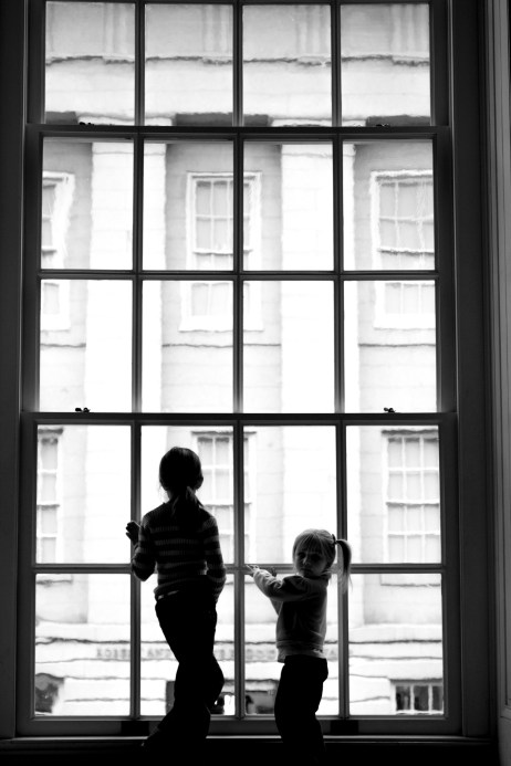 Two girls stand in silhouette in front of a tall museum window. Not So SAHM