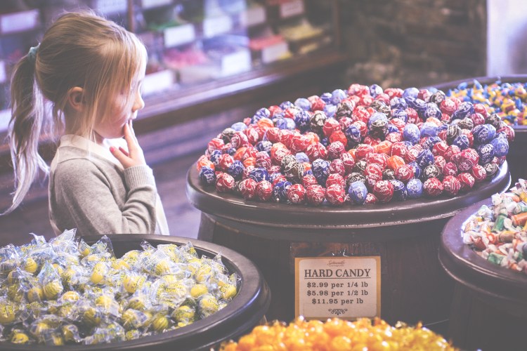 Girl stares at Tootsie Roll Pops in River Street Sweets in Savannah Georgia. Not So SAHM