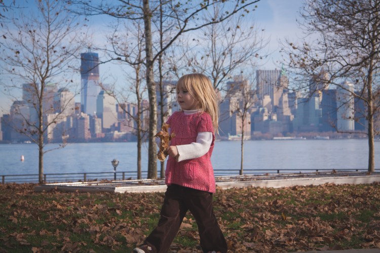 Girl walks with leaf with NYC skyline in background. Not So SAHM