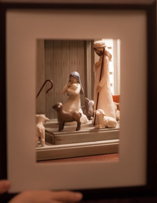Nativity figures are shown behind a frame. Not So SAHM