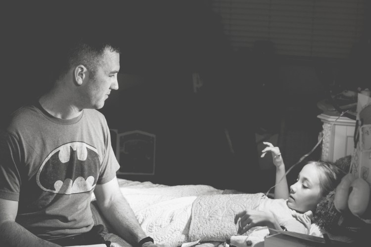 Dad talks with girl as he tucks her in at night. Photo by Not So SAHM